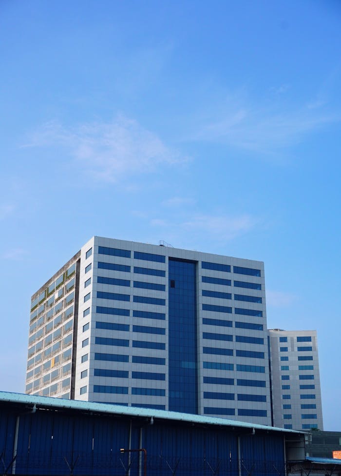 A tall office building in Kochi, India with a bright blue sky background.